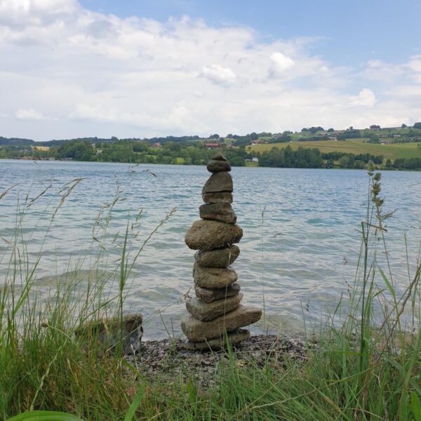 Individuelle schamanische Ausbildung – tiefgehende Transformation und Berufung zum Schamanismus, abgestimmt auf das persönliche Energiepotenzial – Symbolbild: Steinturm vor See als Zeichen für innere Klarheit und spirituellen Weg